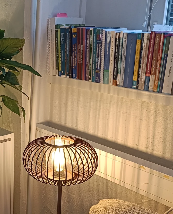 Porvoon vastaanoton nurkka: sytytetty lattiavalaisin ja hyllyllinen psykoterapiakirjallisuutta.